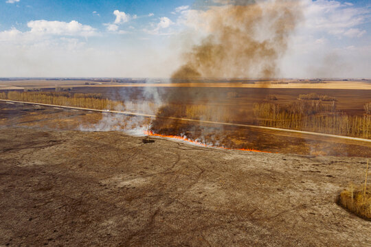 Dangerous fire with gray and brown smoke in countryside in daytime