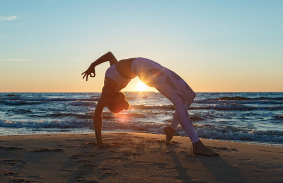 Woman doing yoga during sunset on beach