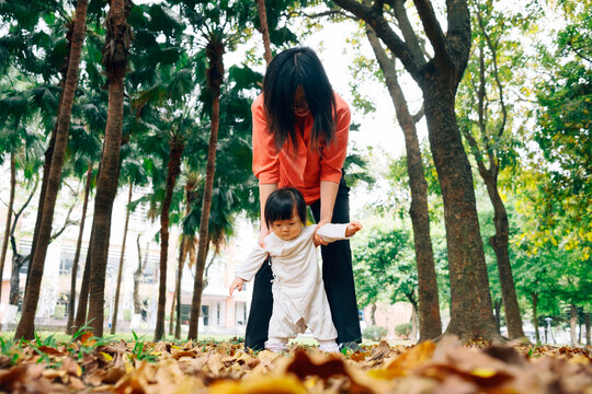 Mother and one year old girl playing and learning to walk