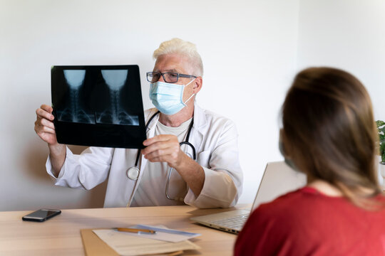 Doctor giving advice to young patient while analyzing medical x-ray