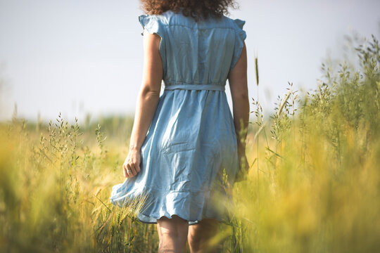 Woman in blue dress walking in agricultural field