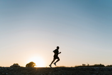 Silhouette of senior athlete jogging against clear sky during sunset