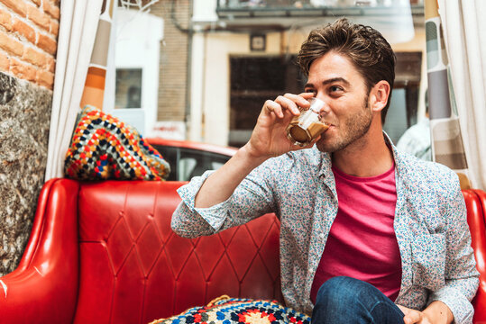 Close-up of mid adult man drinking coffee while sitting on sofa in restaurant