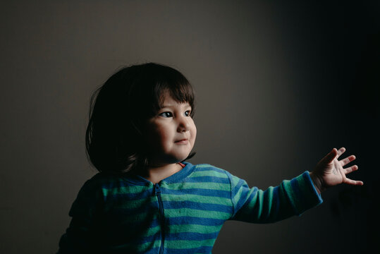 Cute baby girl looking away while standing against gray wall at home