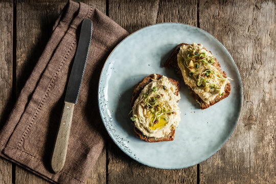 Table knife and bread slices with hummus and sprouts