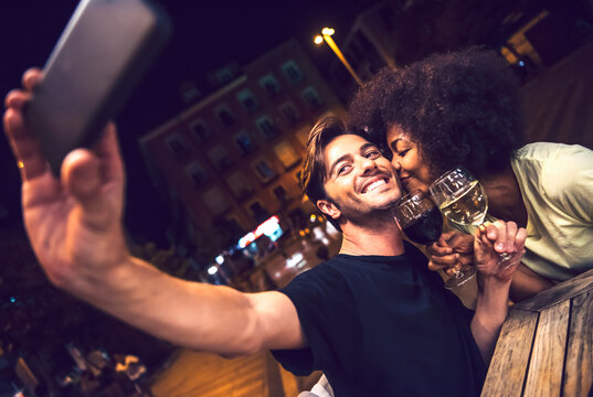 Woman kissing boyfriend taking selfie at date night