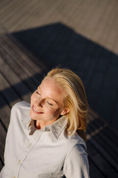 Smiling blond female entrepreneur soaking sunlight in city