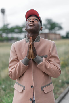 Young man praying with religious faith while standing outdoors