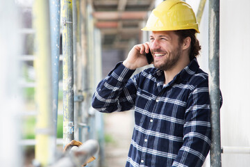 Construction worker talking over smart phone while standing by scaffold at construction site