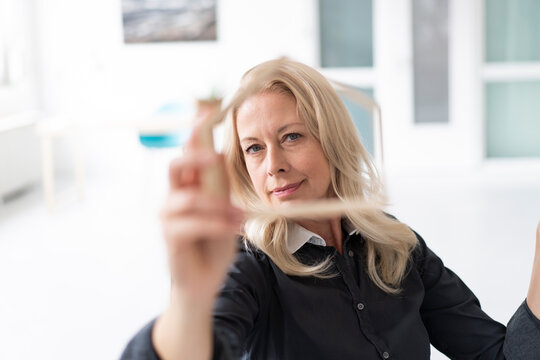 Close-up of confident businesswoman looking through model in home office