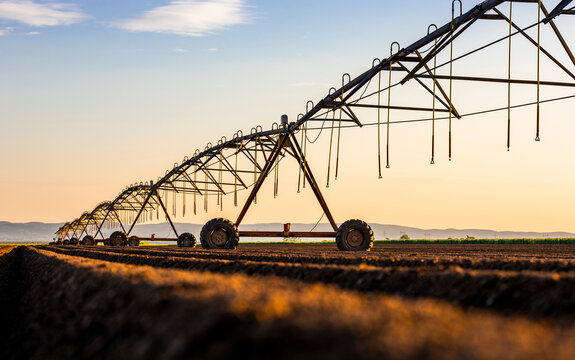 Irrigation equipment on field against sky during sunset