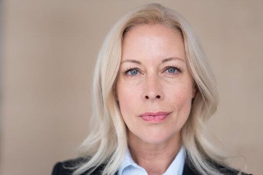 Close-up of confident female entrepreneur with blond hair against wall in office