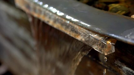 Water fountain edge seen close up with running water on a funnel shape, Handheld shot