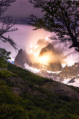 Vertical Rocky snowy mountain peaks with the sun rising behind and red clouds. Fitz Roy in Argentina