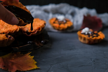 orange cupcakes in tartlets with spider on background of gray web. chocolate is poured on cake. concept of Halloween