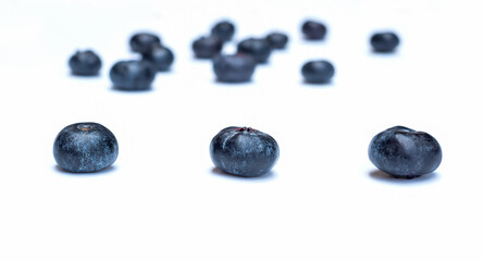 Three blueberries on a white plate in the foreground
