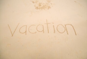 The word VACATION written at sand.