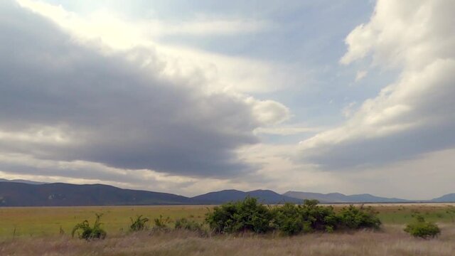 Panoramic view of open fields and mountain range in the background while on a road trip (slow motion)