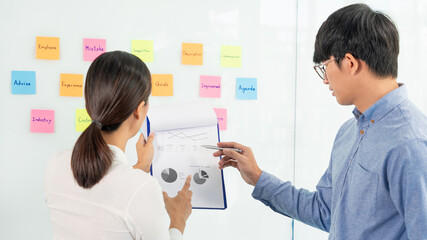 business teamwork in meeting and adhesive stick note on mirror board discussting with team in office room for collecting some idea brainstorming plan.