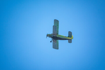 Retro green biplane plane in the blue sky