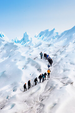 grupo de personas en fila subiendo por el hielo hacia la sima del glaciar Perito Moreno, en la patagonia Argentina