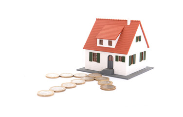 Euro coins laid out as arrow symbol pointing at house model on white background
