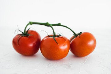 whole food diet concept, close-up of three tomatoes on vine on white minimalist background