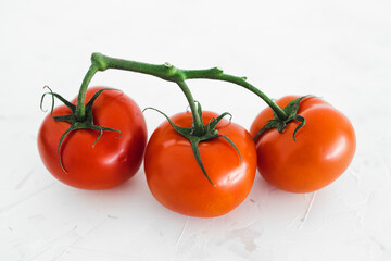 whole food diet concept, close-up of three tomatoes on vine on white minimalist background