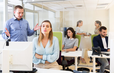 Outraged businessman expressing dissatisfaction with work of frustrated young woman in modern office