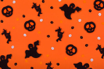 Halloween pattern background made of decorative ghost, witch, skeleton silhouette and pampkins confetti.