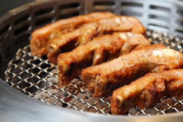 Pork steaks cooking over grill. Side view.