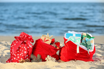 Santa Claus bags with gifts on beach