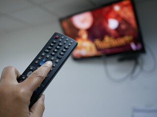 closeup of hand with the remote control television and presses the button.