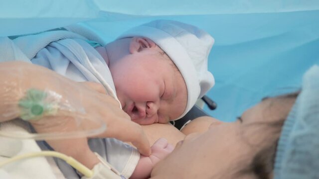 Close up shot of a newborn baby sleeping with skin contact from the mother minutes after birth.