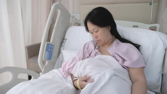 Camera rotates around an Asian mother breastfeeding her child in hospital.