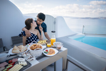 Couple tourist having breakfast on terrace hotel outdoor. Luxury and delicious food. Santorini, Greece.