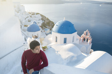 Man tourist visiting whitewashed village, blue domes in Oia, Santorini Greece. mediterranean sea.