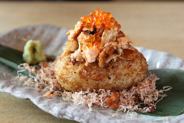 Onigiri topped with salmon roe (ikura) on the plate. Japanese cuisine. Pescatarian snack. Lunch Illustration. Triangle rice balls wrapped with nori seaweed.