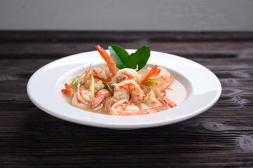Tom Yum Goong Clear Spicy Sour Soup on wooden table top view, Thai local food
