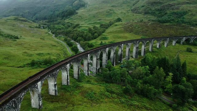Glenfinnan Viaduct Over River Finnan By The Lush Green Mountains In The Highlands Of Glenfinnan, Scotland, United Kingdom. Railway Bridge In Harry Potter Movies - aerial drone, Mavic Air 2