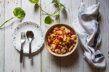 Italian delicacy pasta in a bowl along with condiments on a background. 