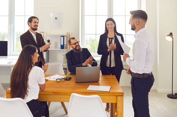 Business team applauding coworker for interesting presentation in corporate meeting in modern office