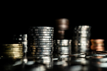 Stack of different coins on dark background.