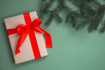 Christmas composition. Gifts with a red bow, spruce branch, New Year's decorations on a green background. Flat lay, top view, copy space. Winter festive concept.