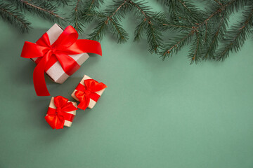 Christmas composition. Gifts with a red bow, spruce branch, New Year's decorations on a green background. Flat lay, top view, copy space. Winter festive concept.