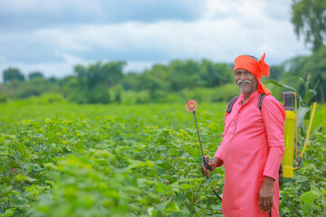 indian farmer spraying pesticide at cotton field