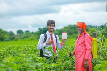 Young agronomist with farmer showing fertilizer botle in field