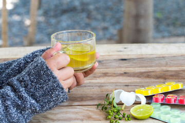 hand of woman holding herbal healthy drinks hot honey lemon and lozenge for health care sore throat of lifestyle woman relax in winter season on table
