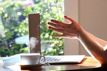 Woman working at home with laptop and a hot water drink