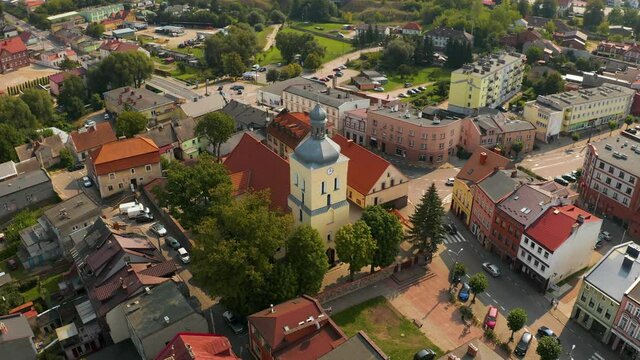 Vehicles Travelling On The Road Near The Roman Catholic Church Of St. Wojciech At The Small And Historical Town Lidzbark Warminski At Daytime In Northern Poland. - aerial drone shot